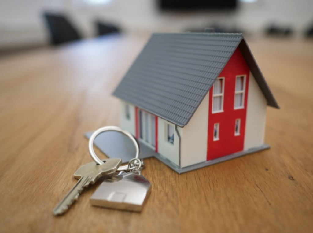 small red and white house, plans, magnifying glass and piggy bank