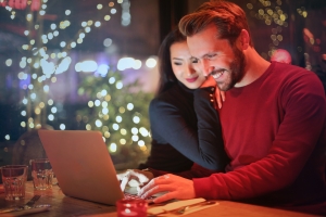 Happy couple researching hidden costs of homeownership in Jamaica on a laptop.