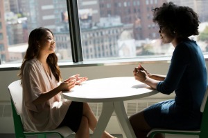 Two women sitting at a table and talking 