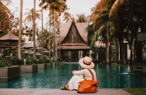 Woman in hat with the bag resting near a turquoise pond.